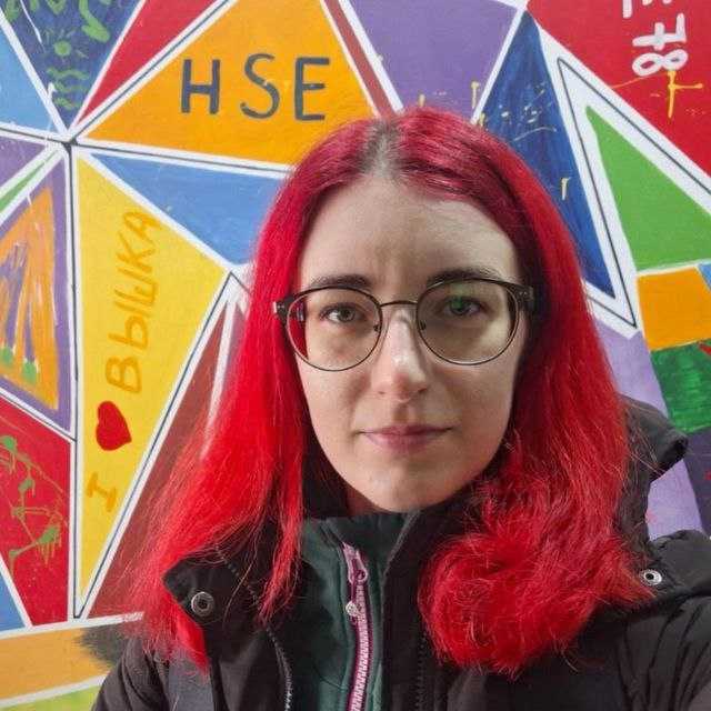 Молодая девушка с красными волосами, в очках и тёплой куртке