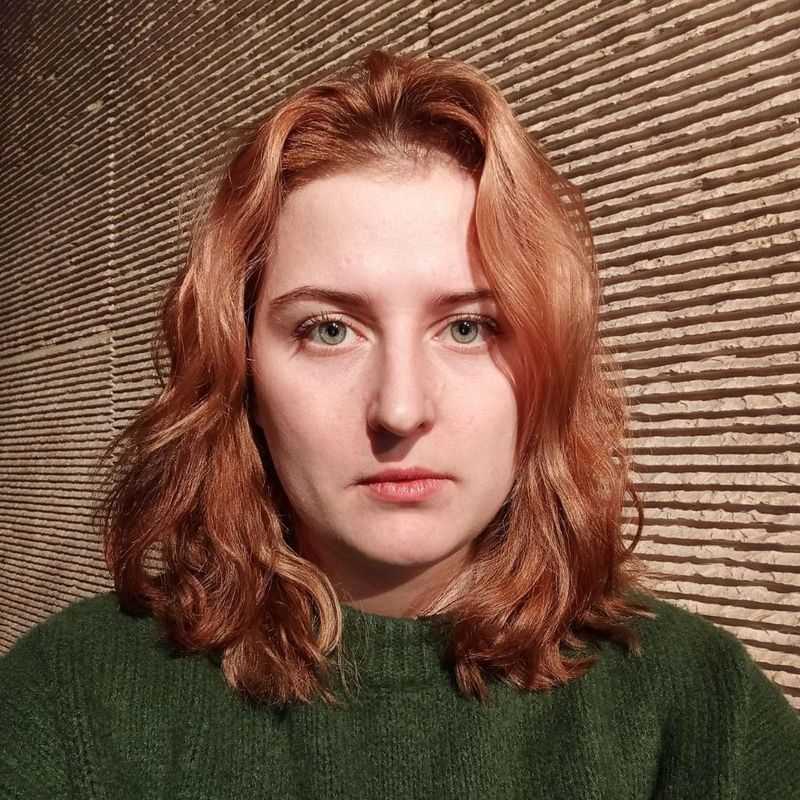 Молодая женщина со рыжими волосами задумчиво смотрит вперёд